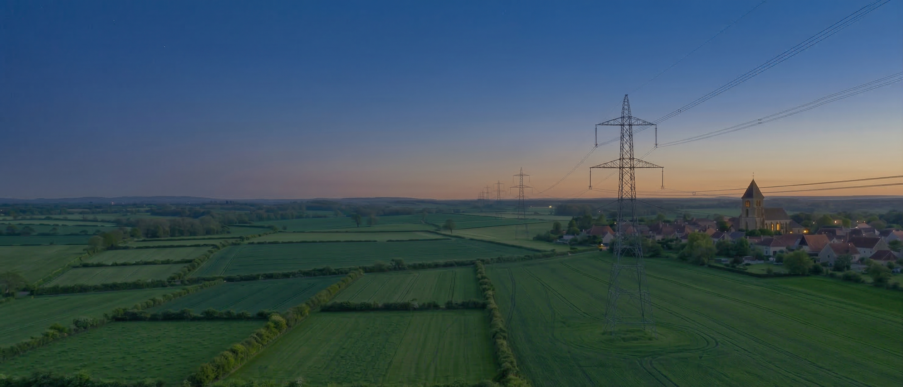 Vue aérienne de lignes électriques haute tension sur des champs